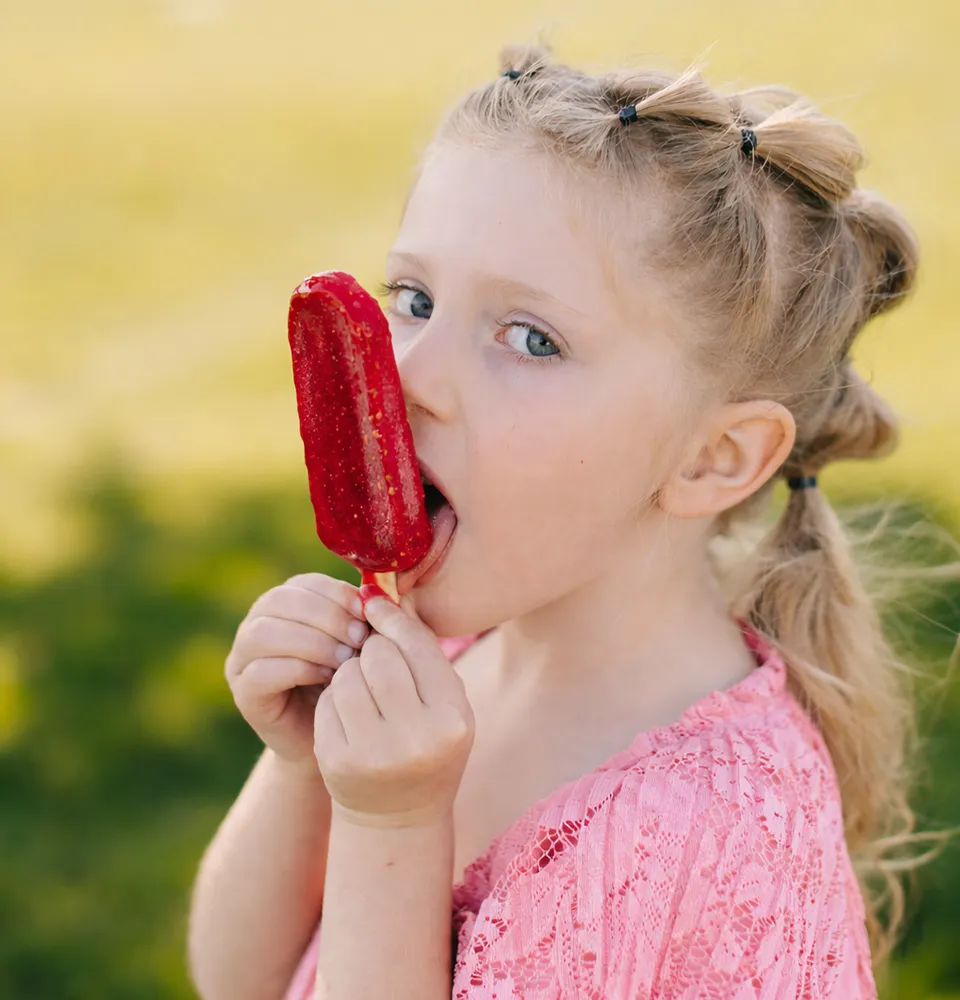 Little girl eating a raspberry fruit pop